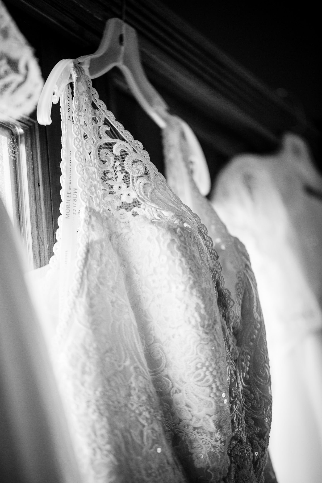 A close-up detail of an elegant white lace and beaded wedding dress showing intricate embroidery patterns.