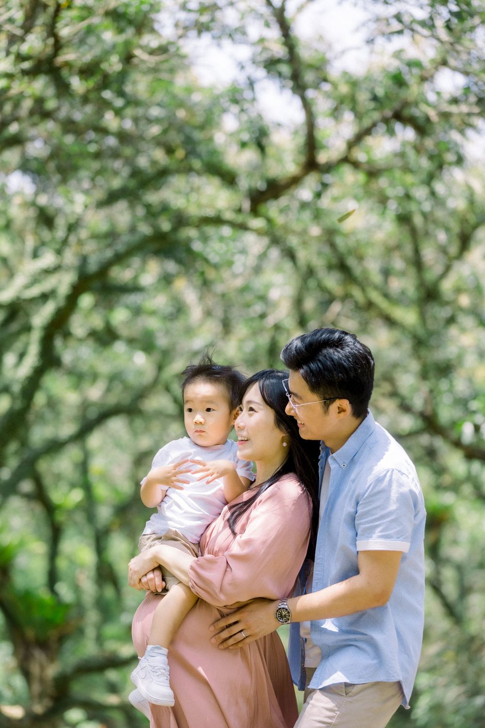 A family enjoys a tender moment together outdoors in a lush green garden setting.