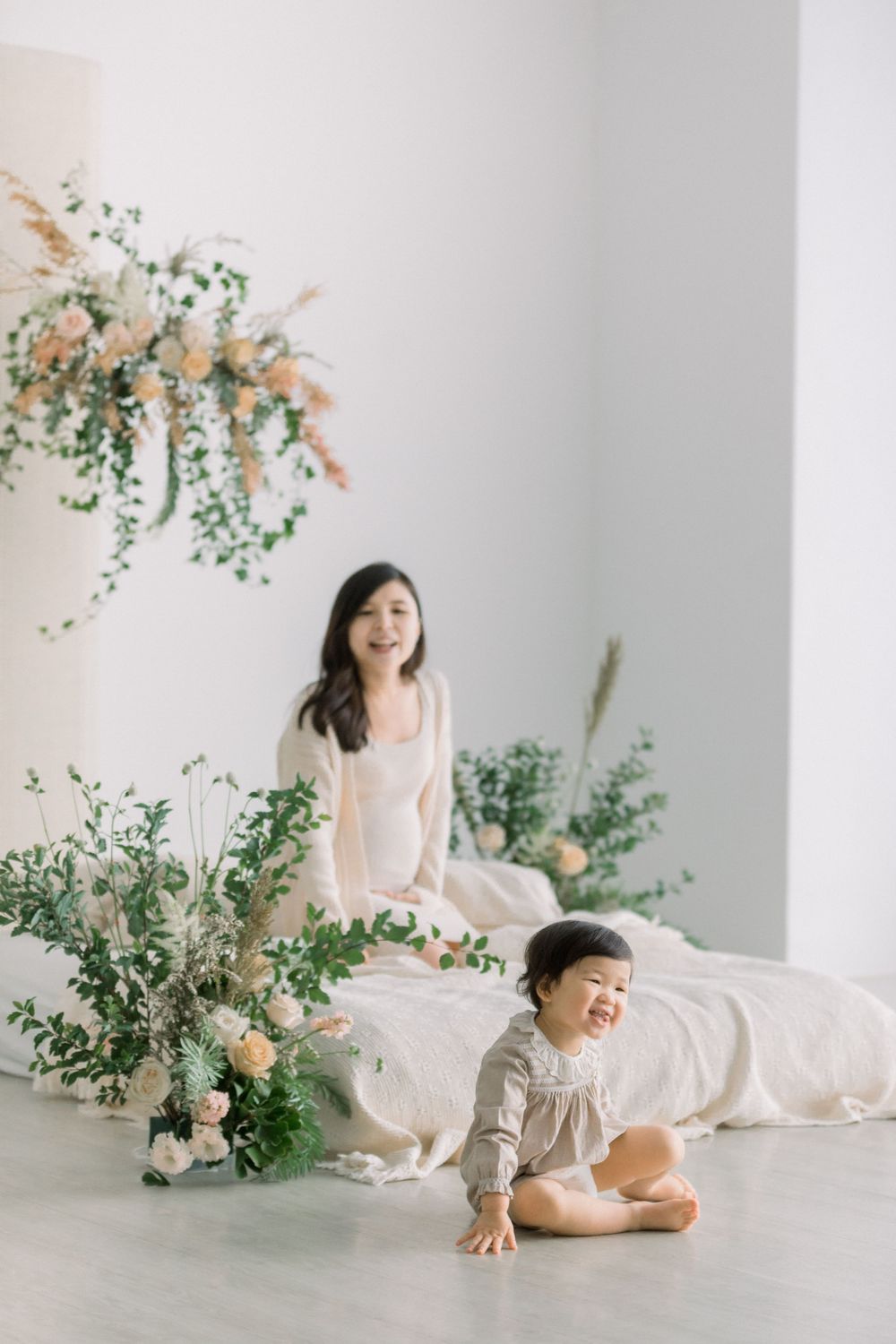 A minimalist studio photoshoot with soft floral arrangements and white decor creating an ethereal atmosphere.