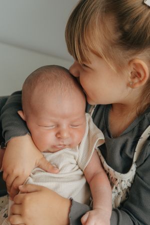 A series of tender moments showing a parent holding and bonding with a sleeping newborn baby in a cozy setting.