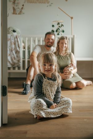 Indoor photoshoot sequence showing family playtime on hardwood floor with white furniture in background and natural lighting.