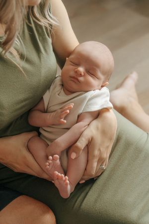 A tender series of photos showing a sleeping newborn baby being cradled and held against soft green fabric.