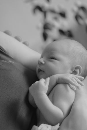 Close-up black and white image of infant hands reaching upwards.