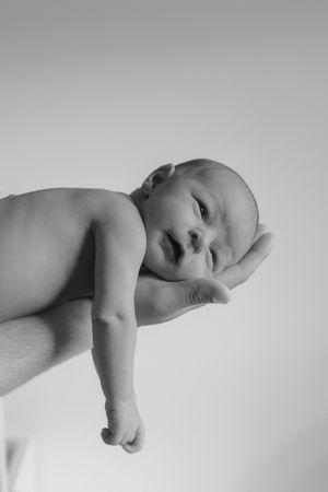 Artistic black and white close-up shots of a sleeping newborn baby against neutral background.