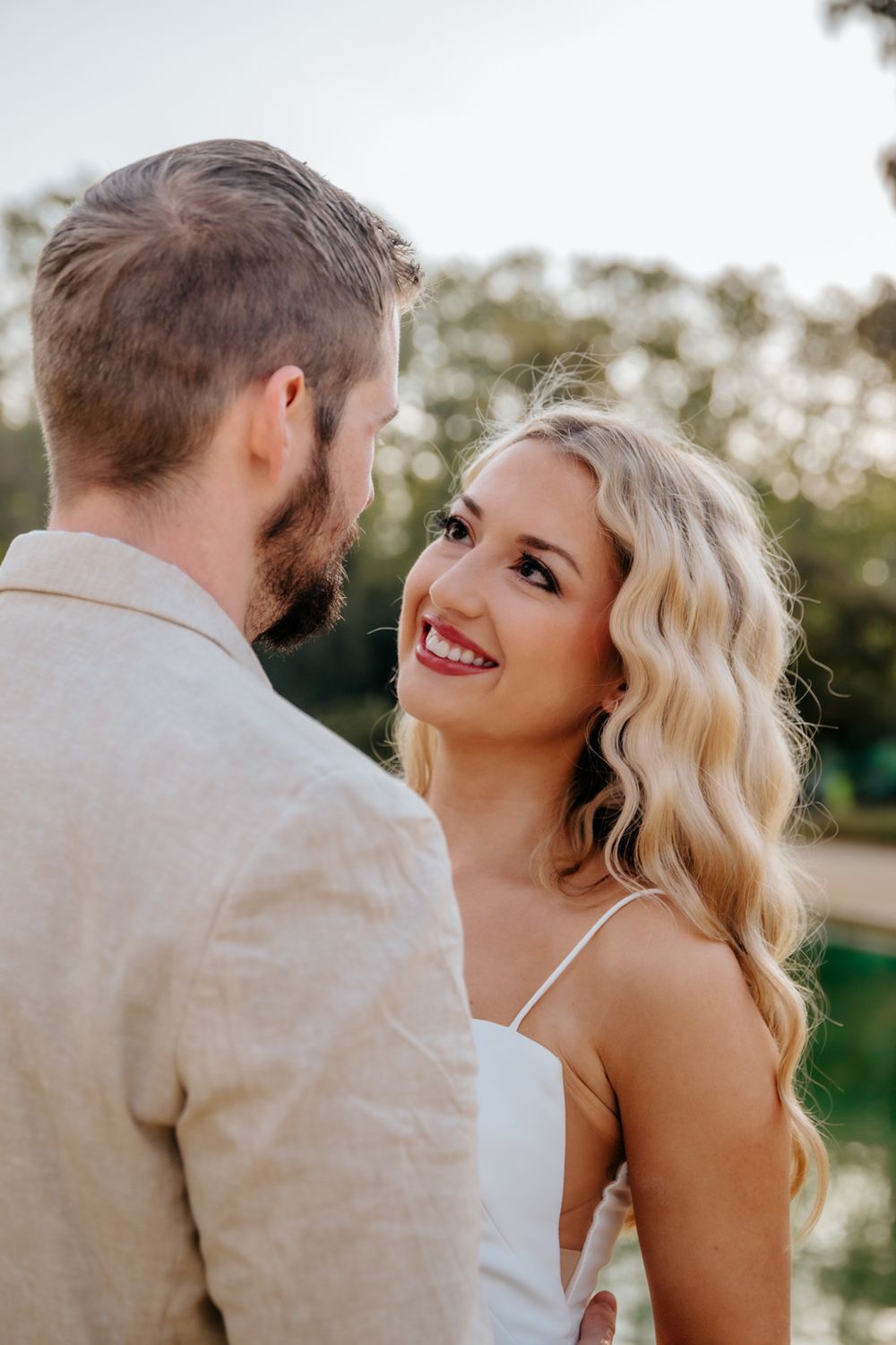 Ashley & Alex smiling and embracing on a scenic path in the park.