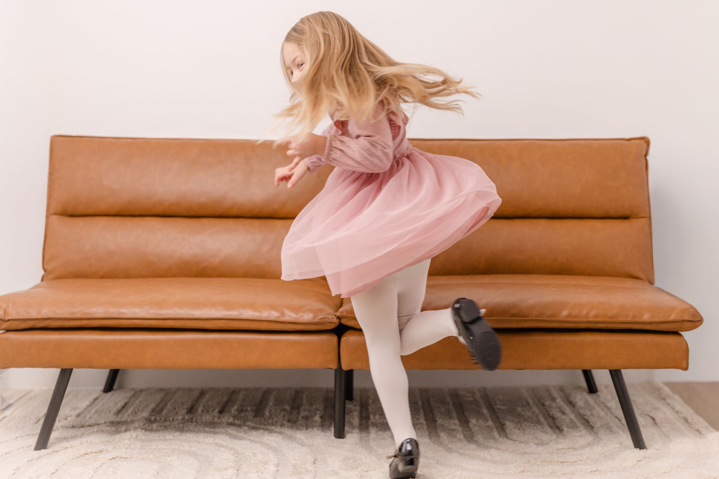 A brown leather mid-century modern sofa shown from different angles against a white wall.