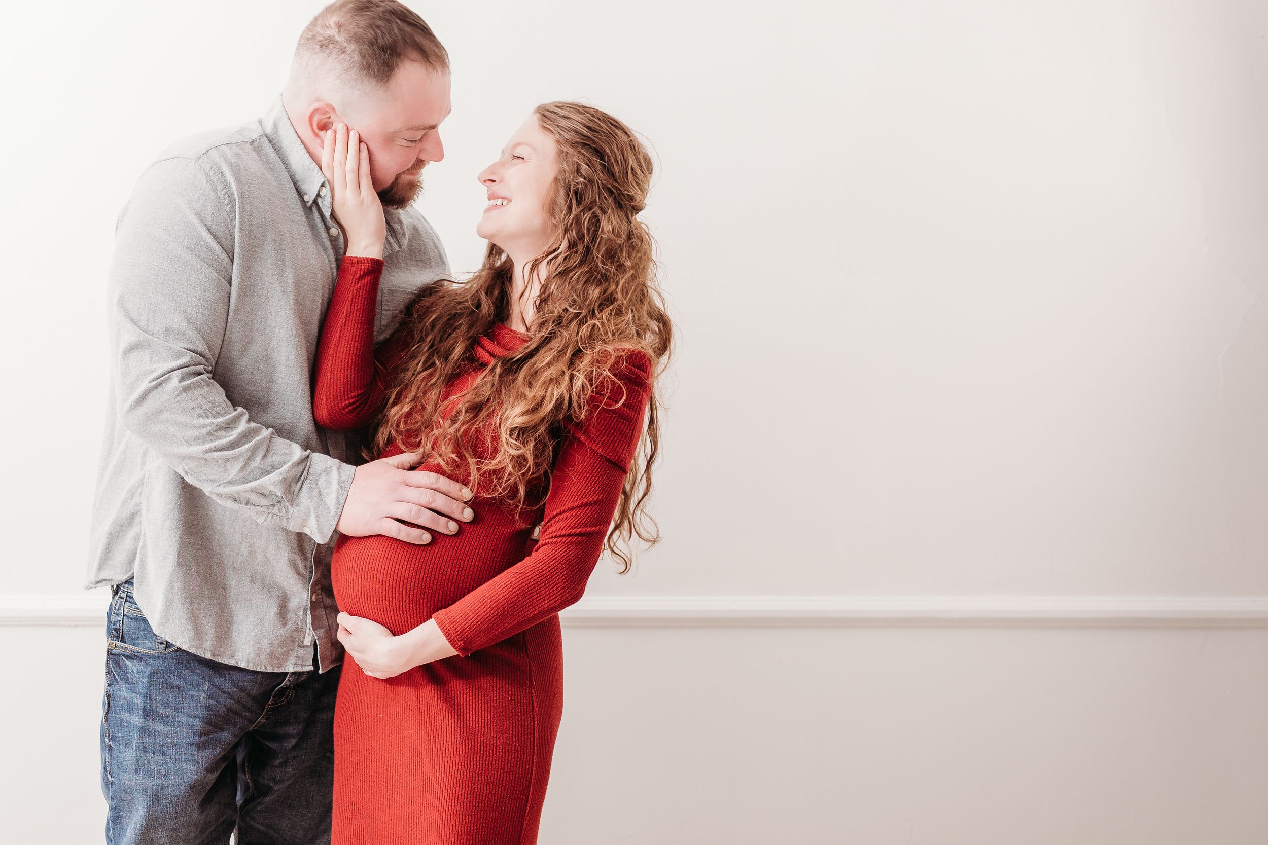 Romantic maternity photo series with couple in red dress and casual attire.