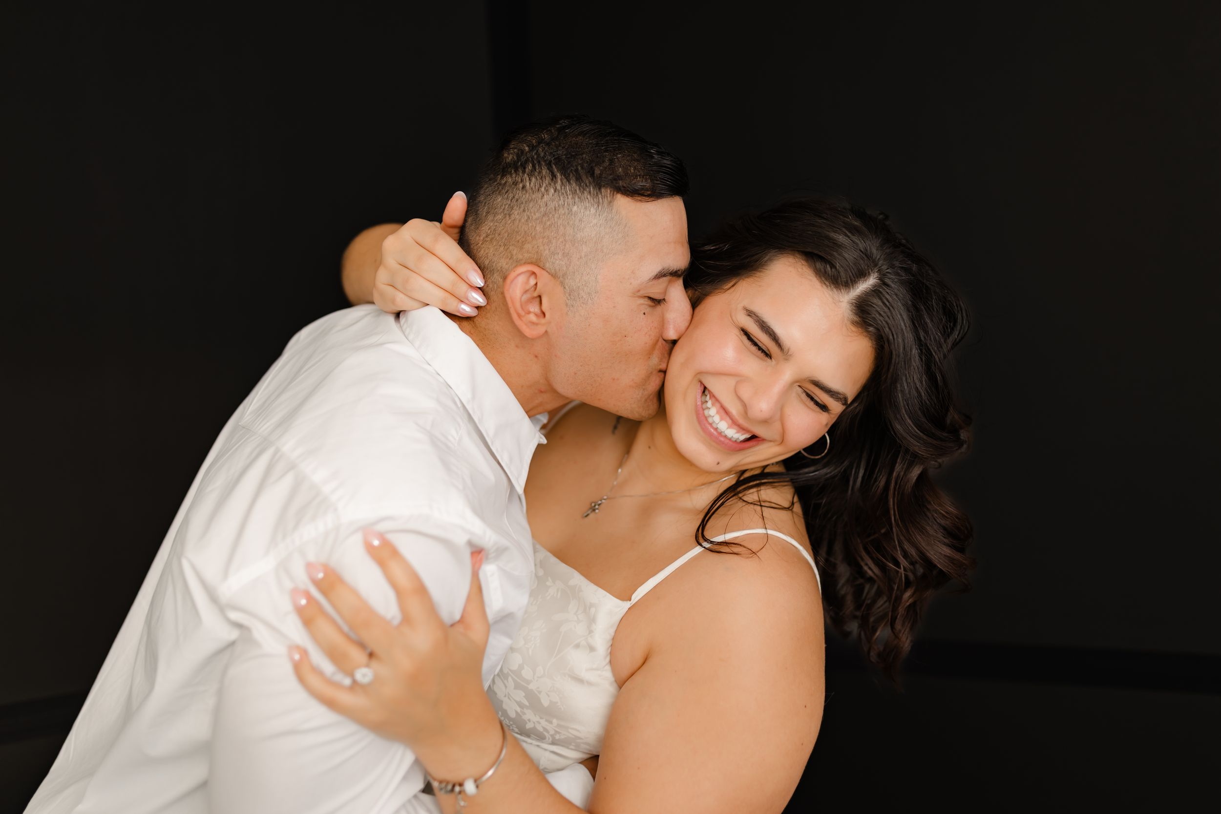 A romantic couple in white embraces and smiles together in a series of intimate black and white photographs.