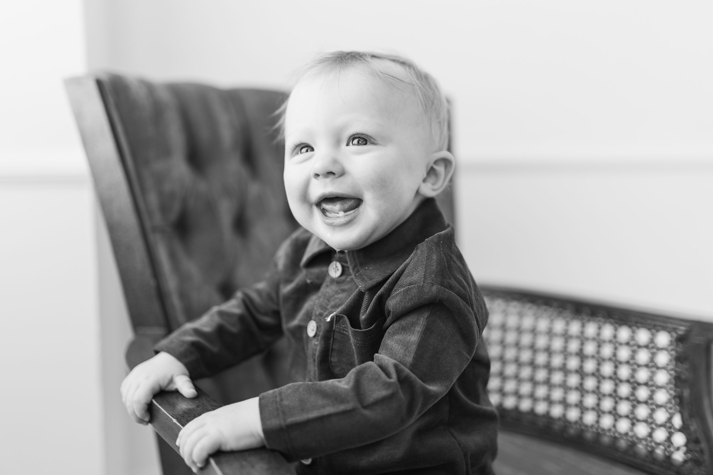 A black and white photo collage showing a baby laughing and smiling in various candid poses.