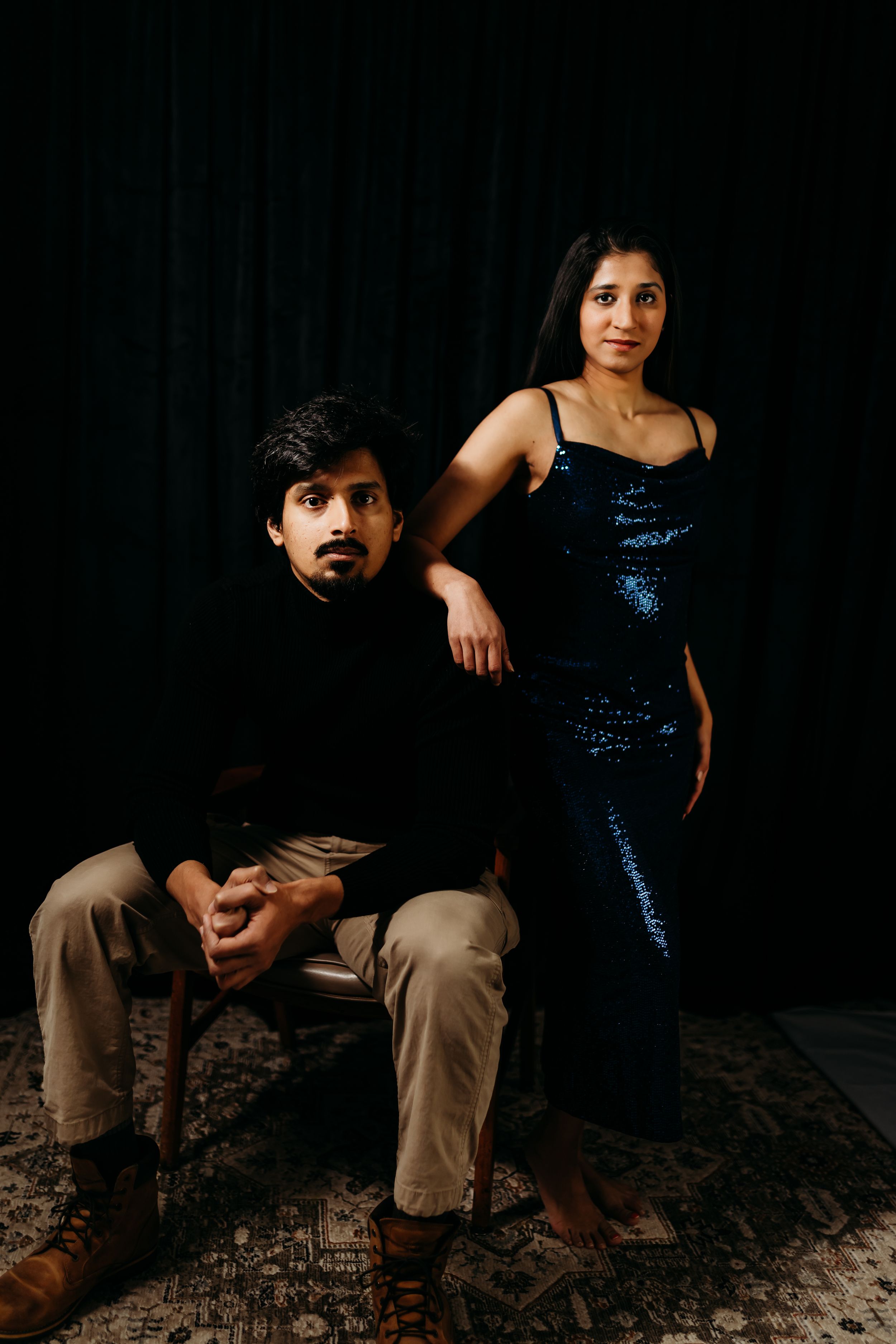 Moody couples portrait session with formal attire against dark background.