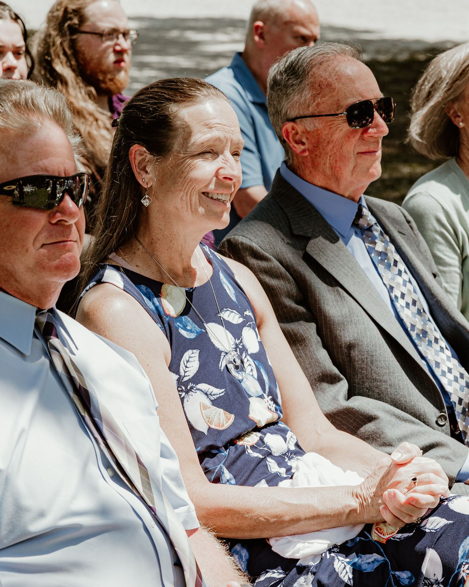 Three people sitting together at an outdoor wedding ceremony expressing joyful expressions. Florida wedding photographer. lithia acres photo