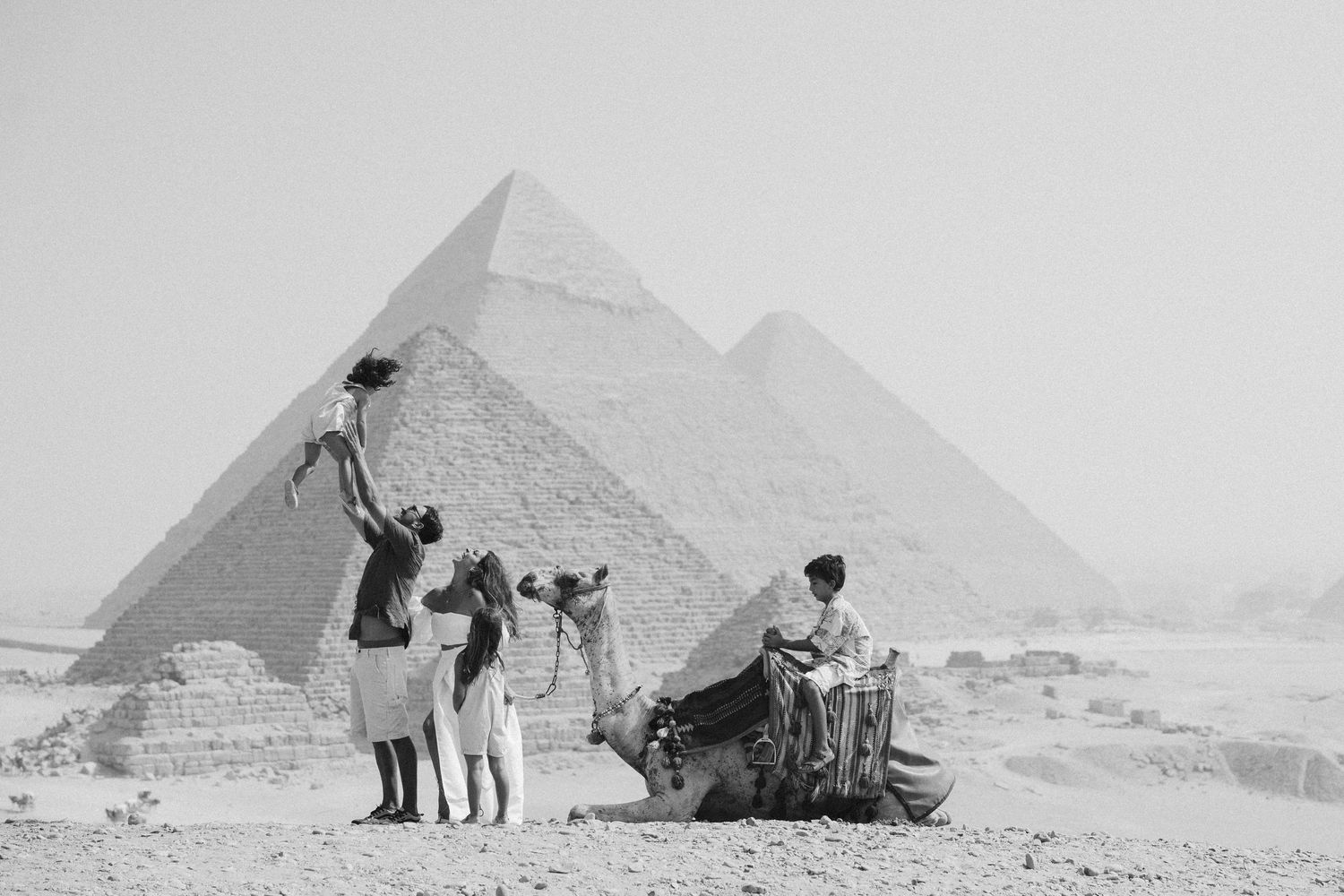 Vintage black and white photos of tourists visiting the ancient pyramids of Giza in Egypt.