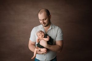 A series of tender moments showing a father holding and comforting a small baby in a studio setting with dark backgrounds.