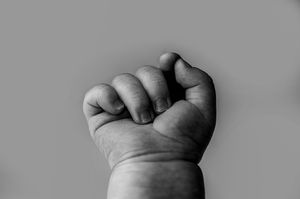 Close-up sequence of hands pinching and squeezing raw clay or dough into abstract organic shapes in black and white.