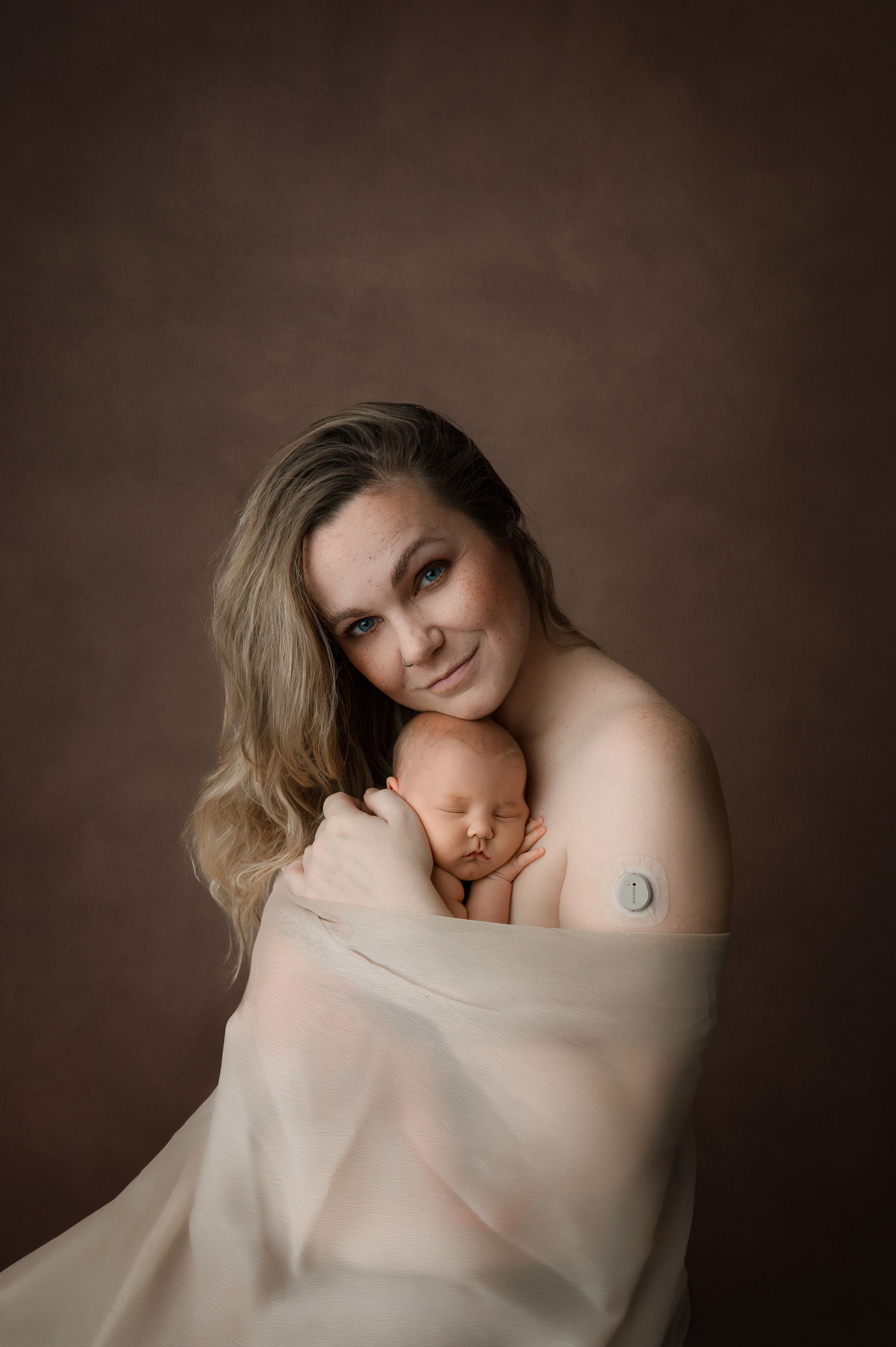Artistic portrait series showing intimate moments wrapped in soft beige fabric against dark brown backdrop.