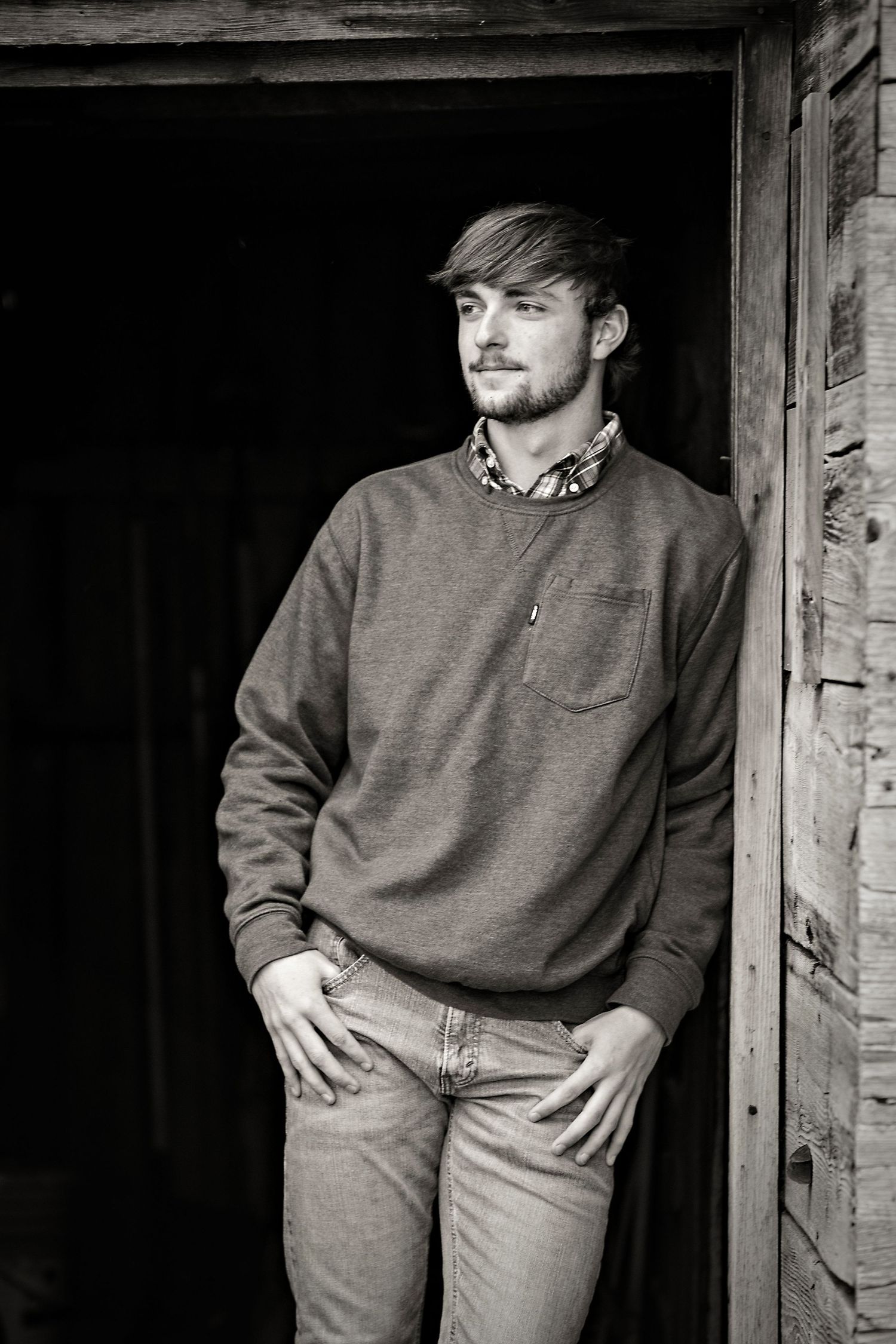 High School Senior boy leaning against a barn