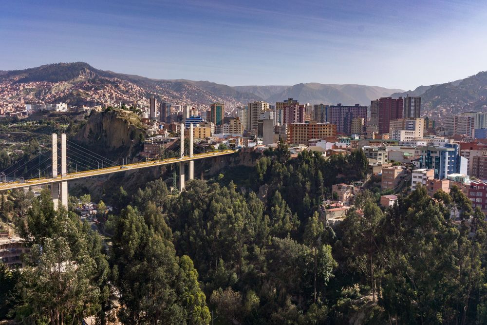 Panoramic cityscape of La Paz Bolivia with mountains in the background and green trees in the foreground.