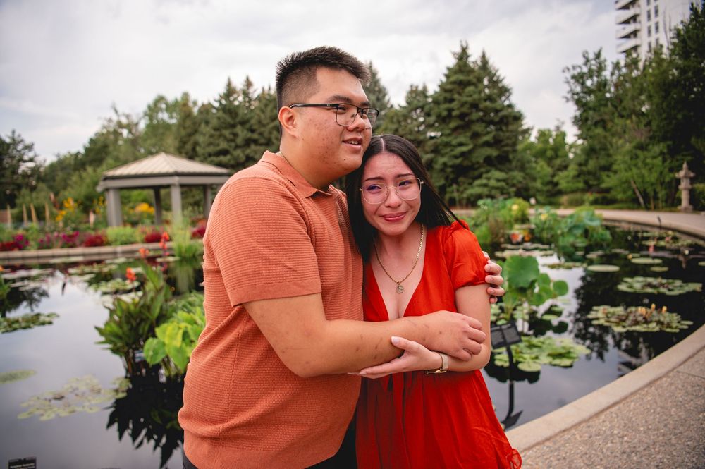 Couple enjoys romantic moments in a lush Japanese garden with scenic water features and walking paths.