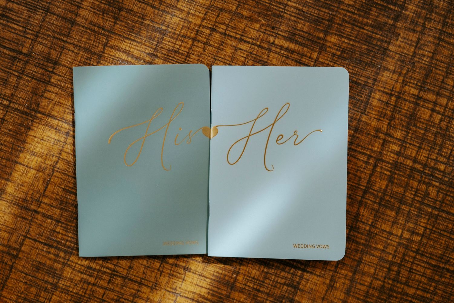 Professional images showing elegant His and Hers wedding cards with calligraphy writing on a wooden surface.