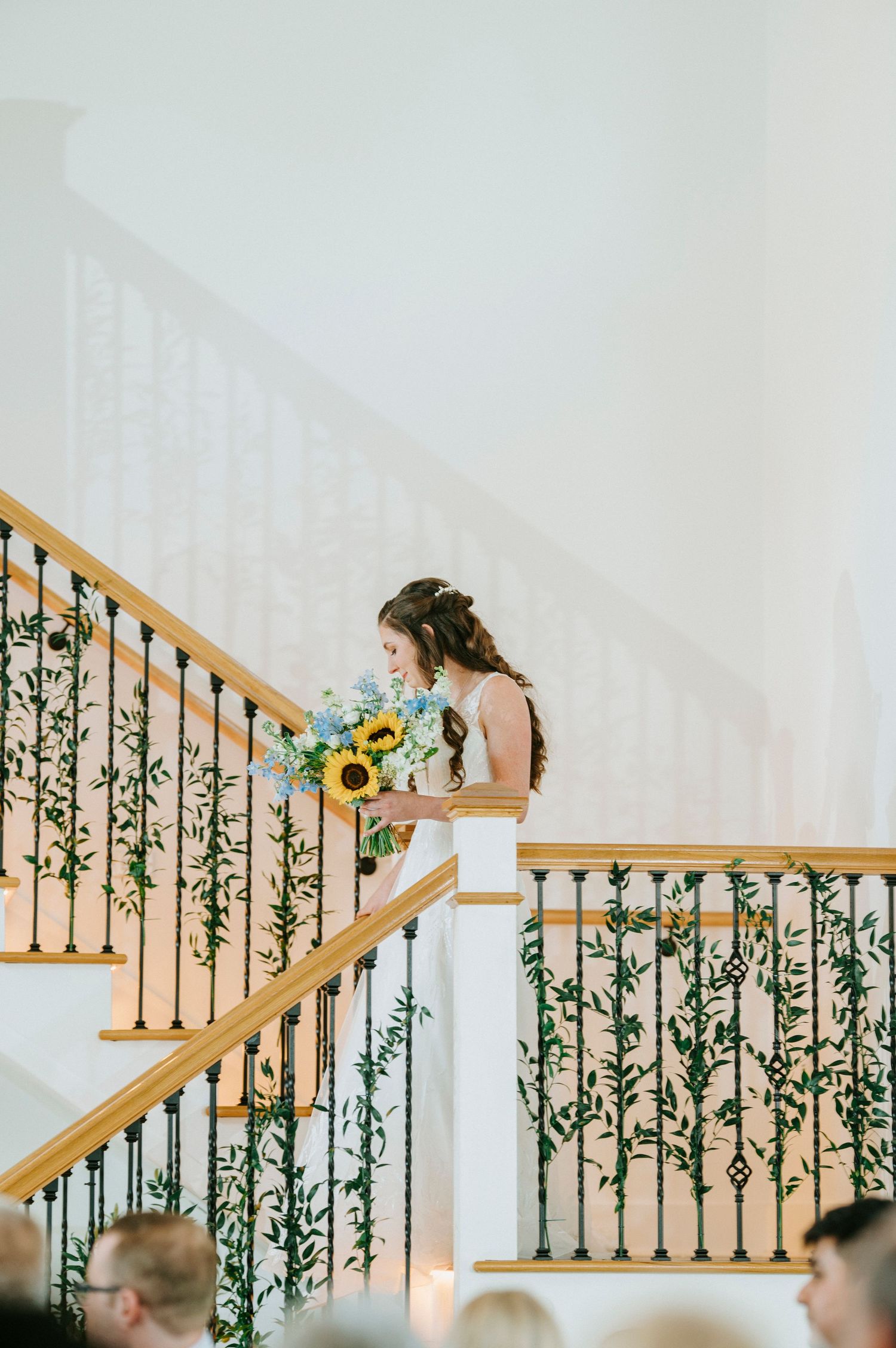 A wedding staircase decorated with greenery vines and sunflowers creates an elegant backdrop.