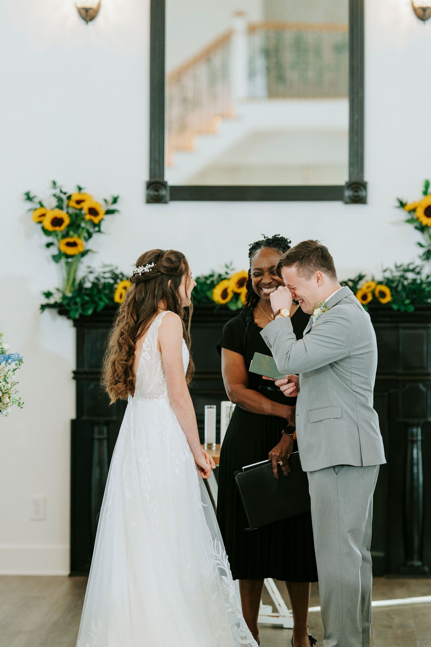 Wedding party participates in emotional ceremony with sunflowers decorating background by pillars.