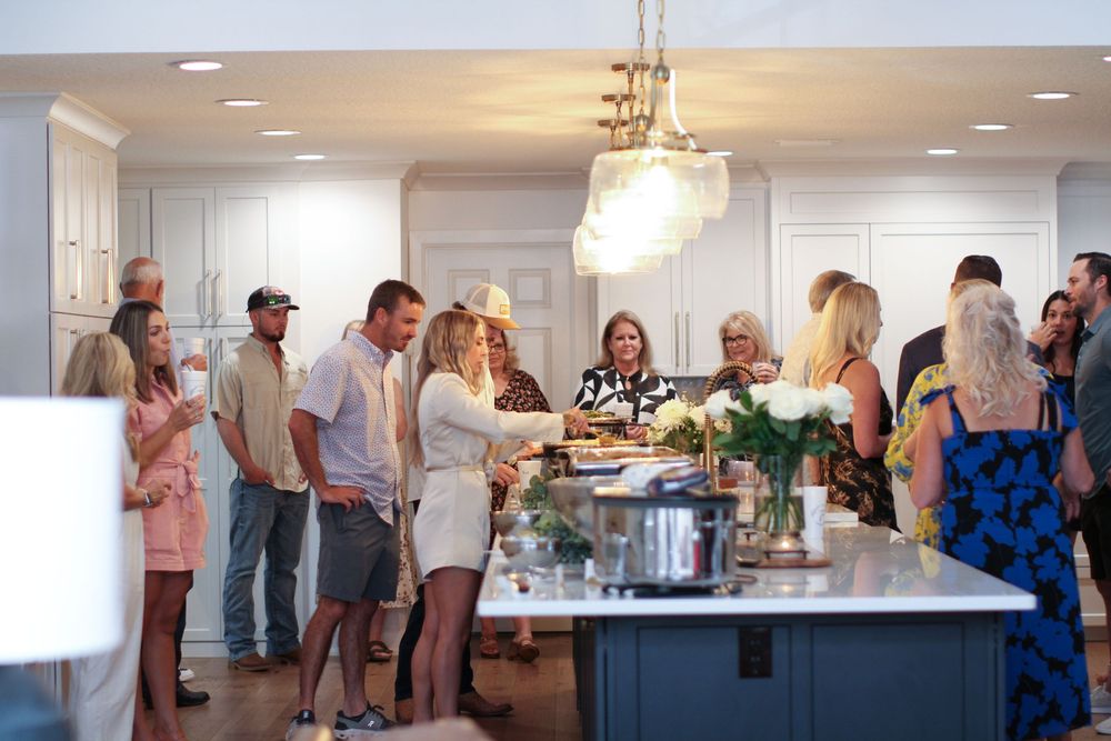 People mingle and socialize during a catered event in an elegant indoor reception space with bright lighting.