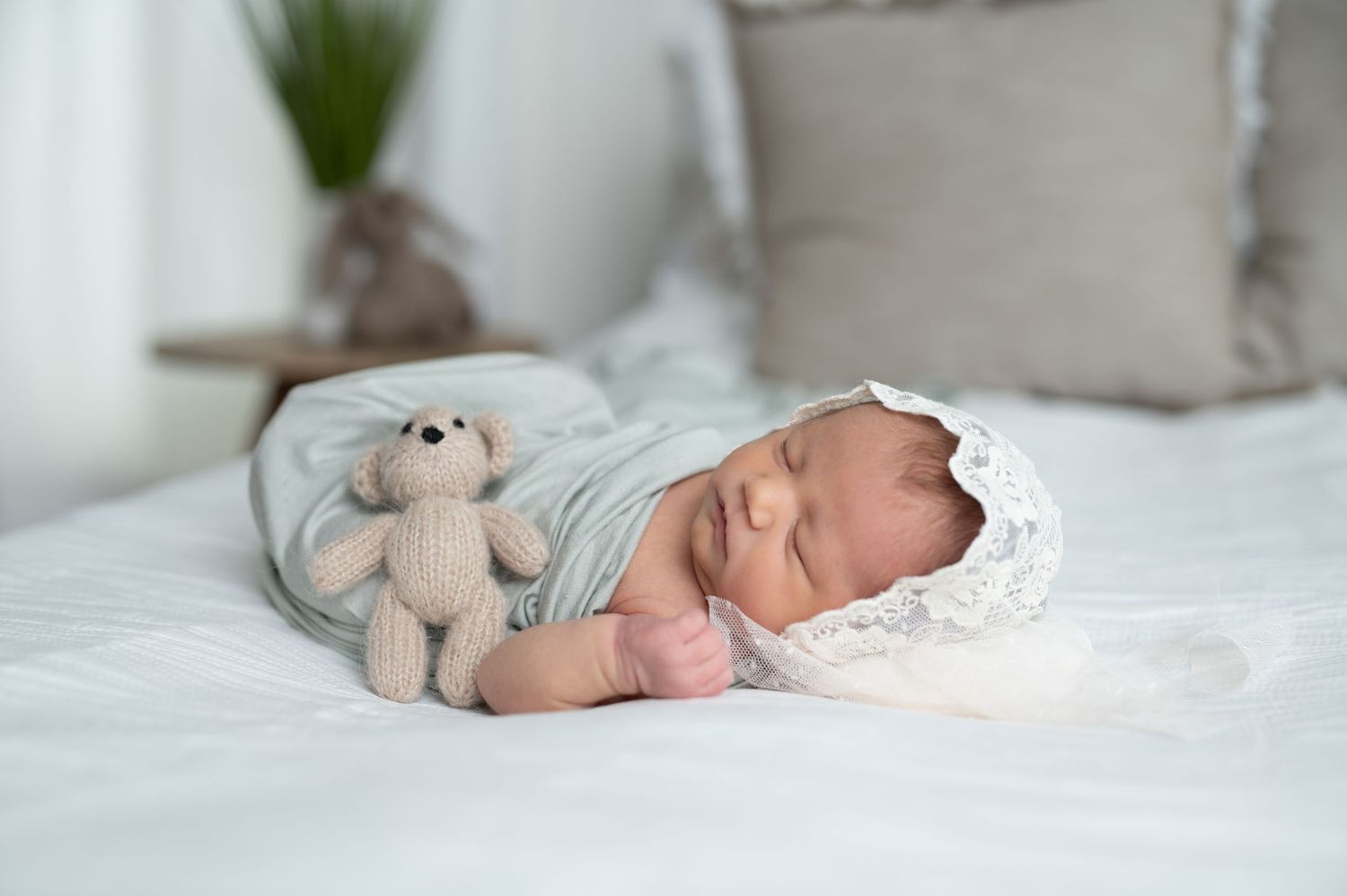 Peaceful newborn baby sleeping on white bedding with plush toy.