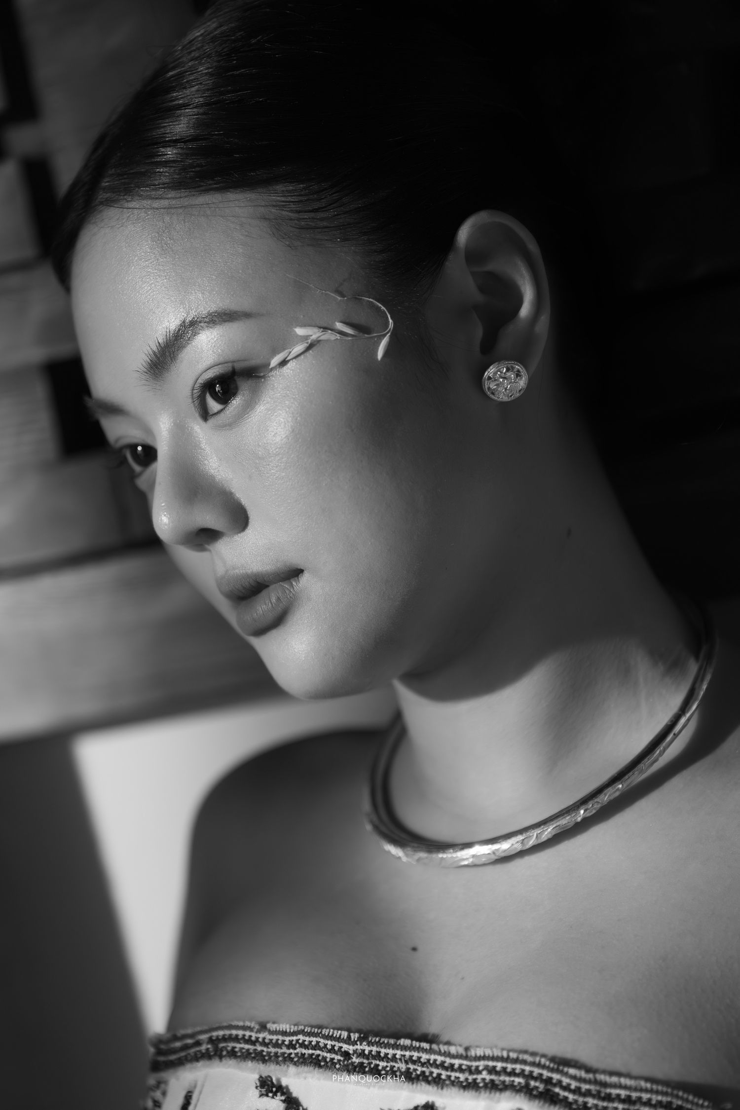 Black and white close-up portrait of Asian bride with silver necklace and eye art.