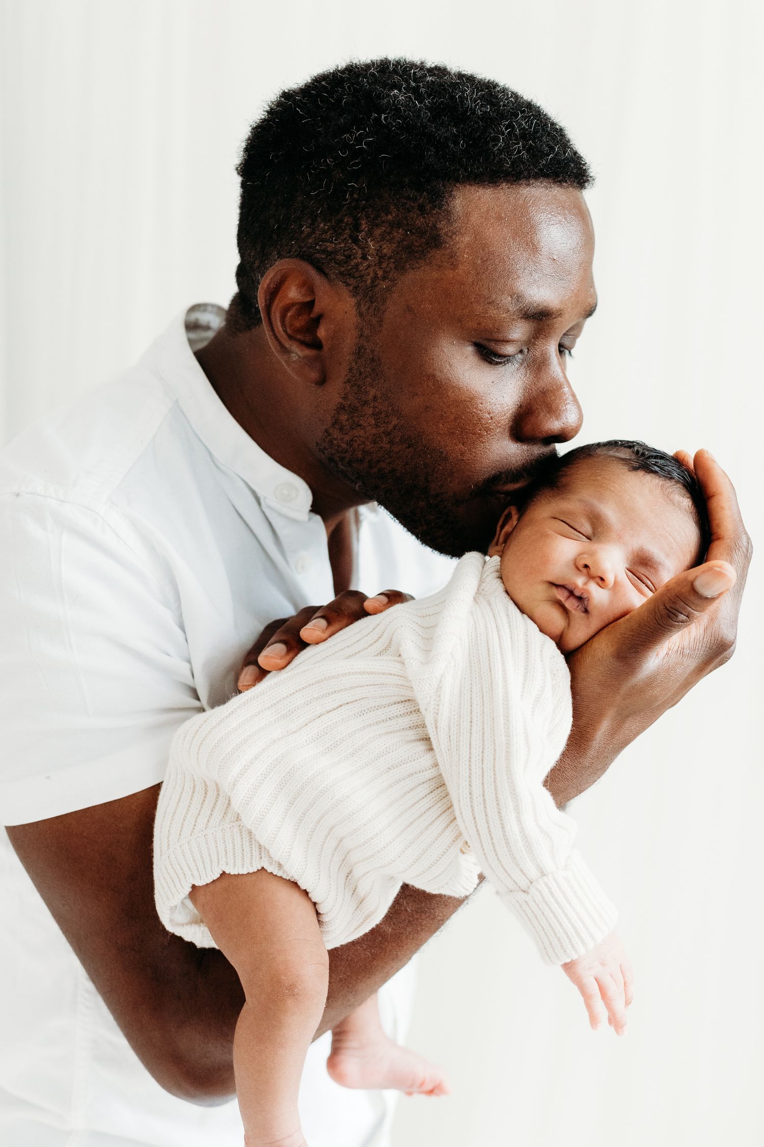 Proud dad cradling newborn baby in Nottingham studio, timeless portraits captured at Mapperley by newborn photographer.
