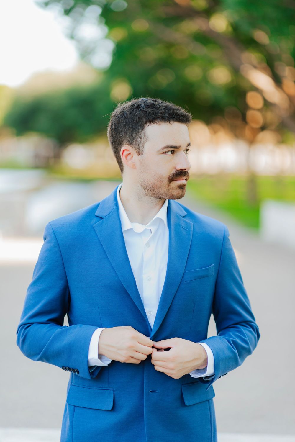 Close-up sequence of someone adjusting the buttons on a bright blue suit jacket.