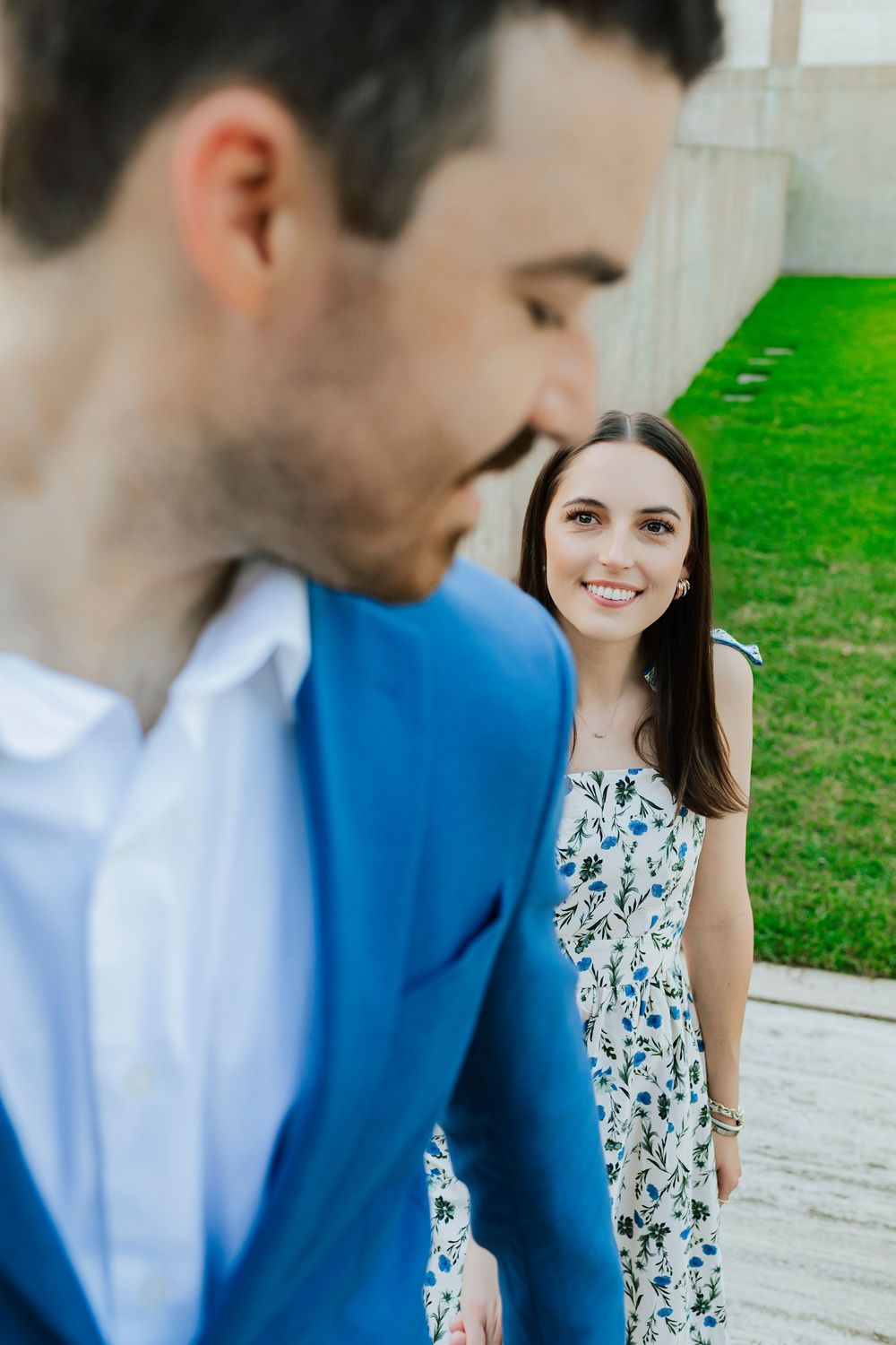 A tender moment captured between a couple wearing blue and floral outfits in an outdoor setting.