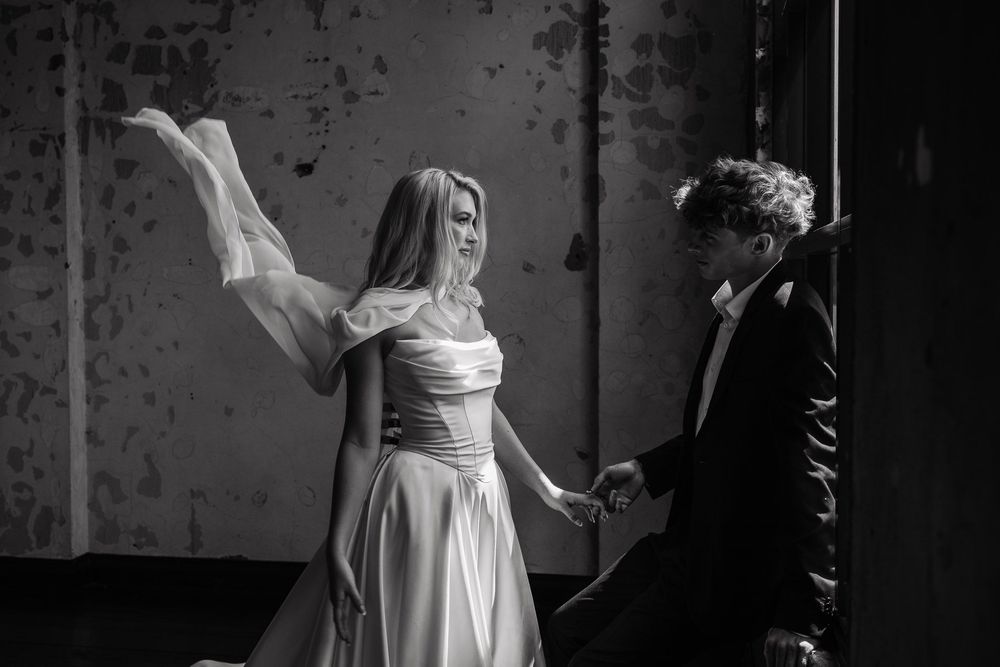 A dramatic monochrome wedding dance photo with a couple spinning in an industrial space.