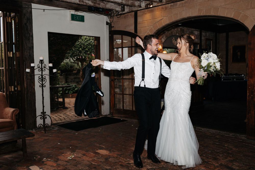 A romantic couple dancing and embracing during their first dance at a rustic wedding venue.