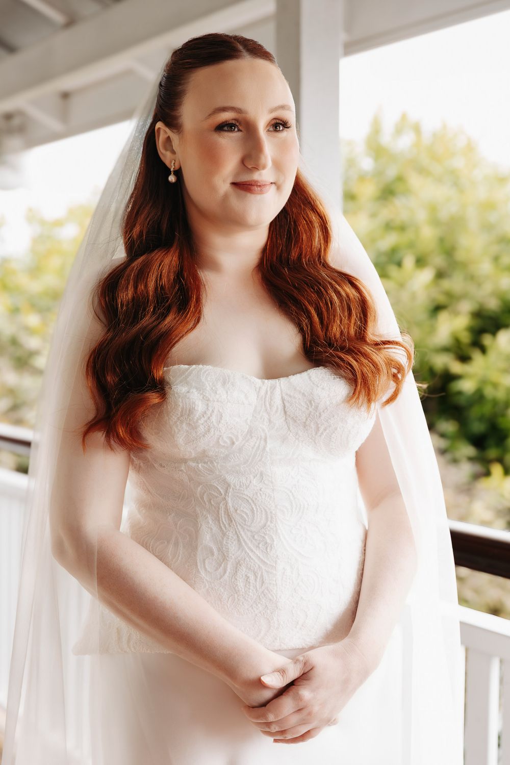 A bride in a white lace wedding dress poses elegantly in a series of outdoor portraits on a porch.