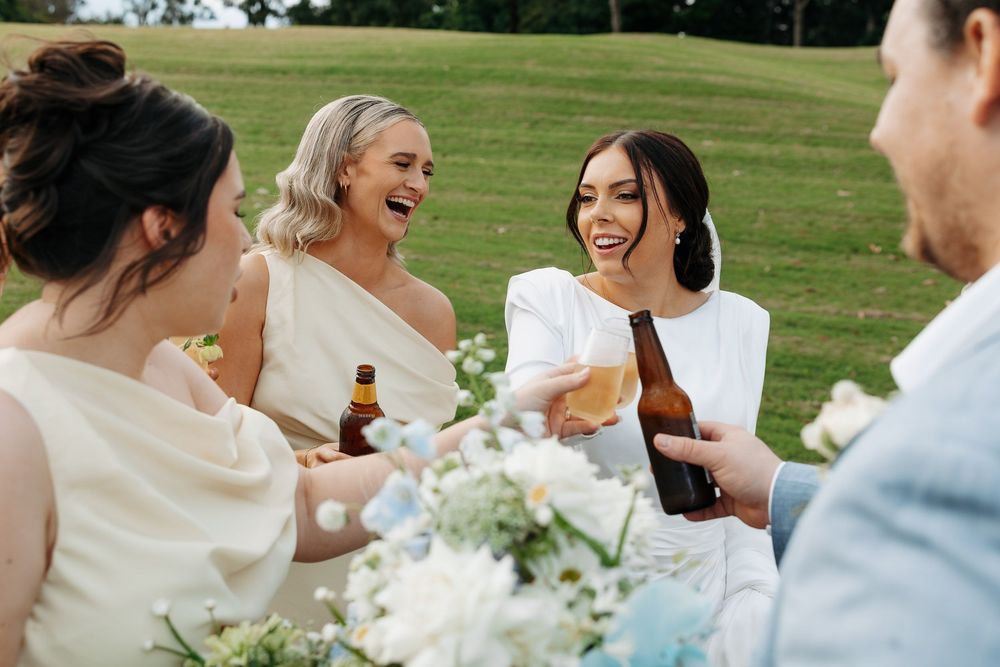 Wedding guests share laughter and drinks during an outdoor reception celebration.