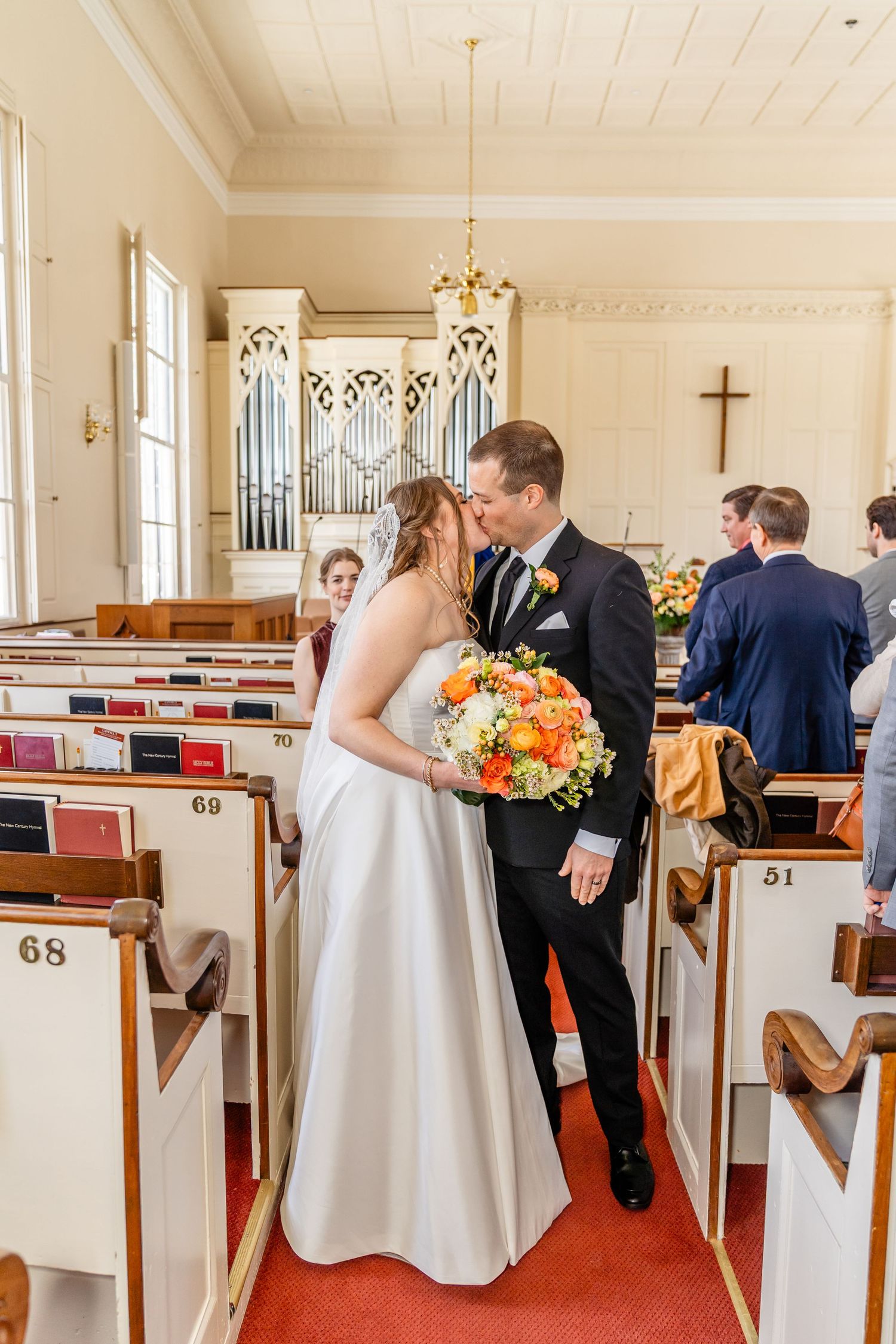 A couple shares a romantic moment in a traditional church with wooden pews and an organ pipe backdrop.