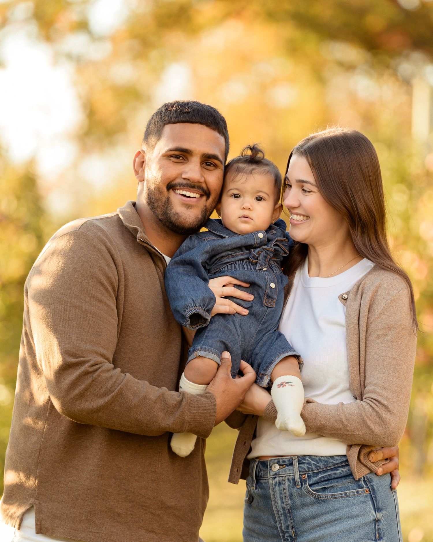 A family shares joyful moments together in an autumn setting with golden bokeh lighting in the background.