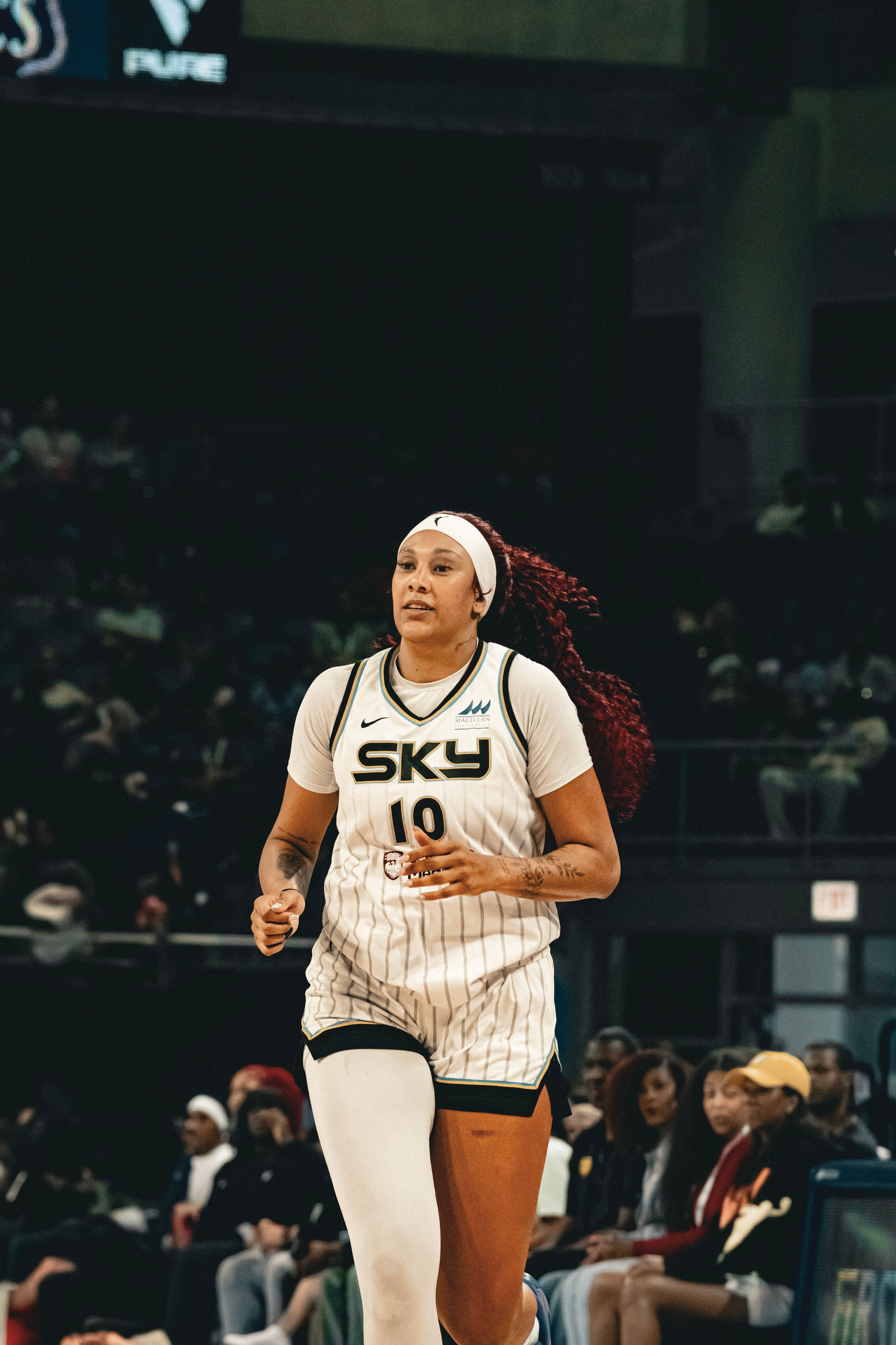 Basketball player in white SK3 uniform sprints down court during professional indoor game.