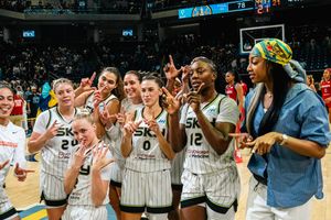 Players and fans celebrate a thrilling sports victory with smiles and cheers on the sidelines of a basketball court.