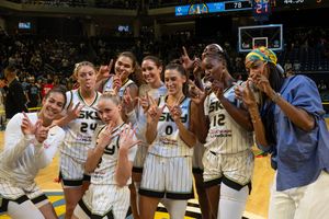 Basketball fans and players celebrate enthusiastically in a crowded arena during an exciting game moment.