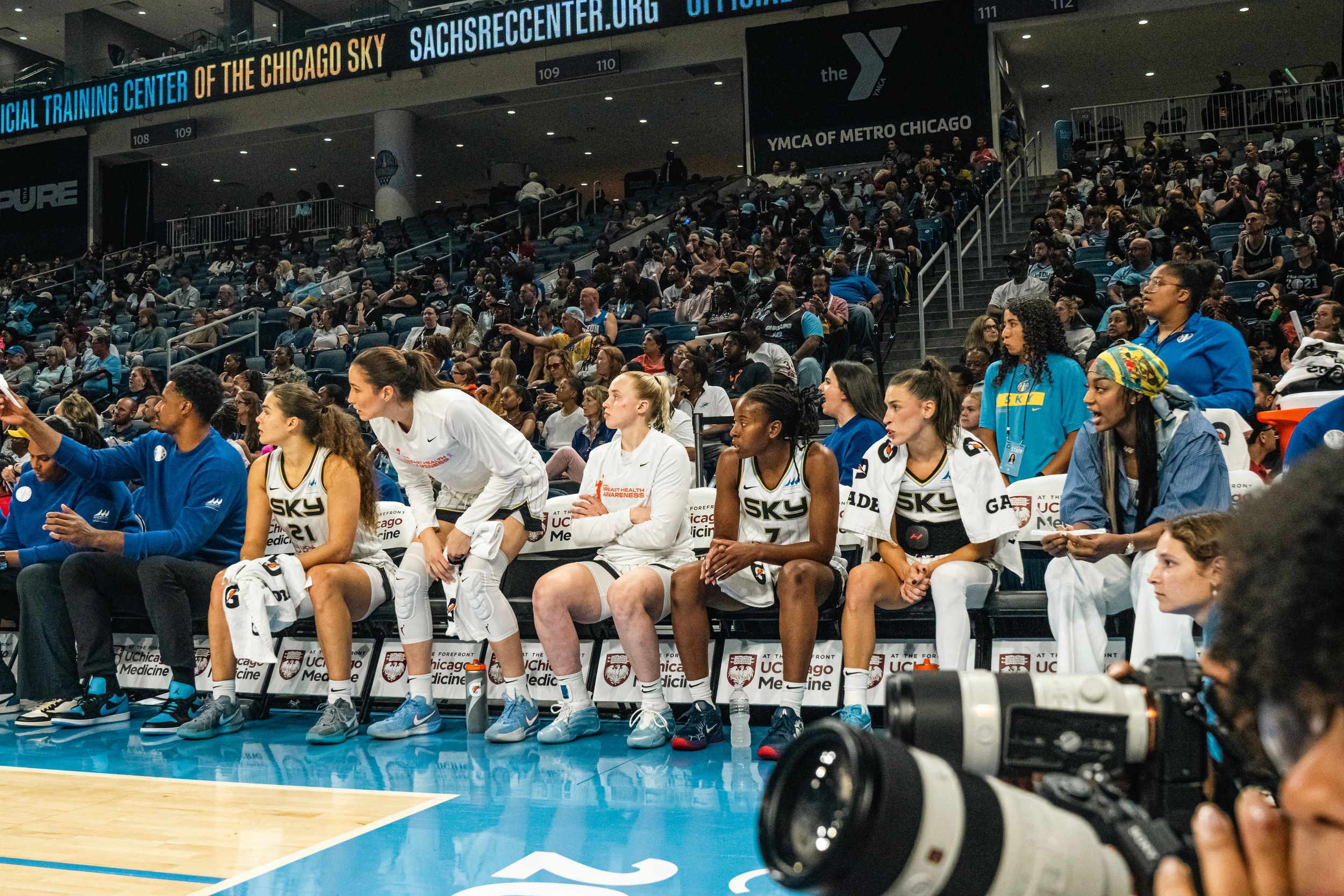 Basketball team celebrates enthusiastically from their bench during an exciting game at an indoor arena.
