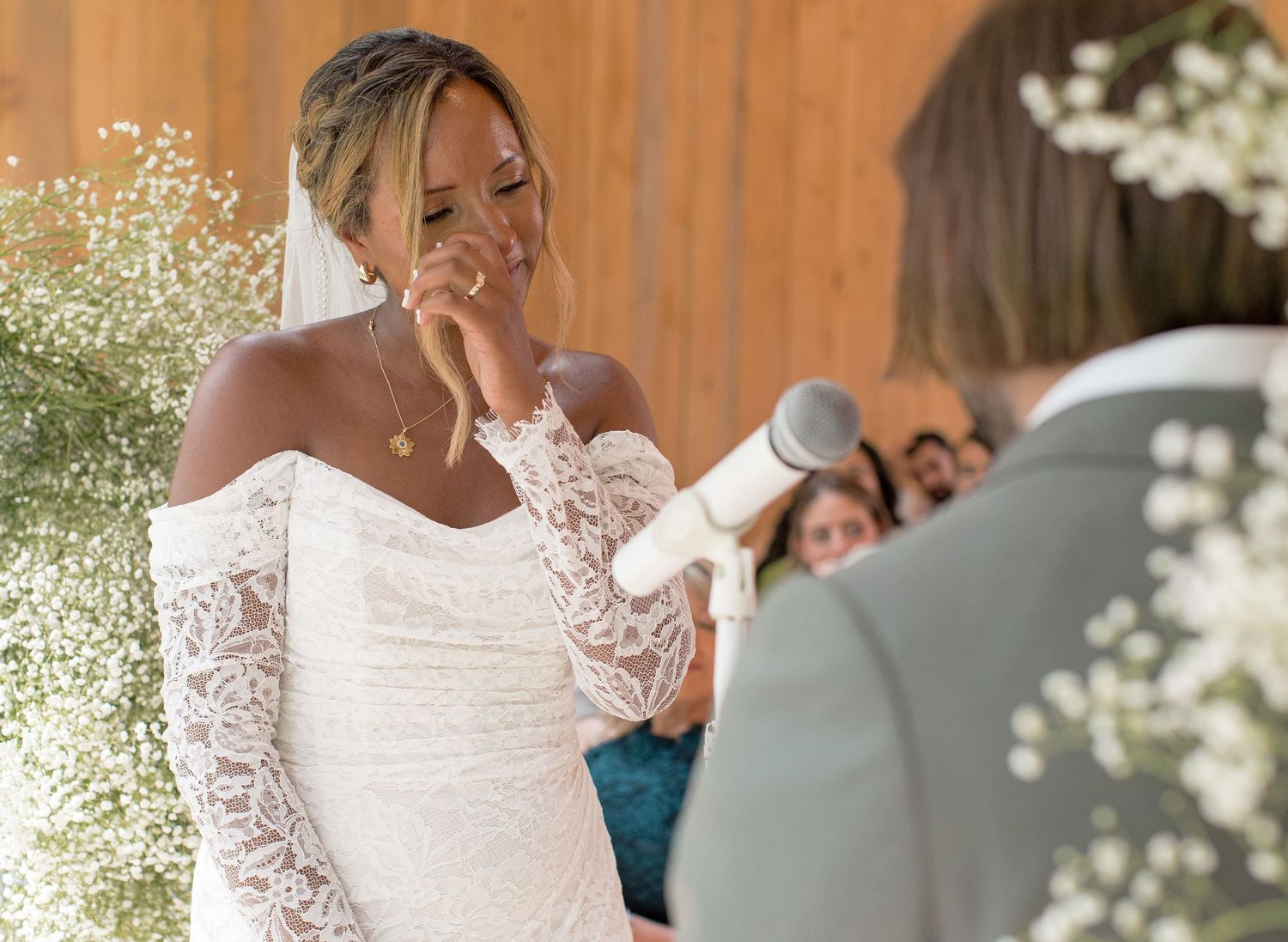 A wedding moment is captured during a beautiful outdoor ceremony in natural lighting with white floral decorations.