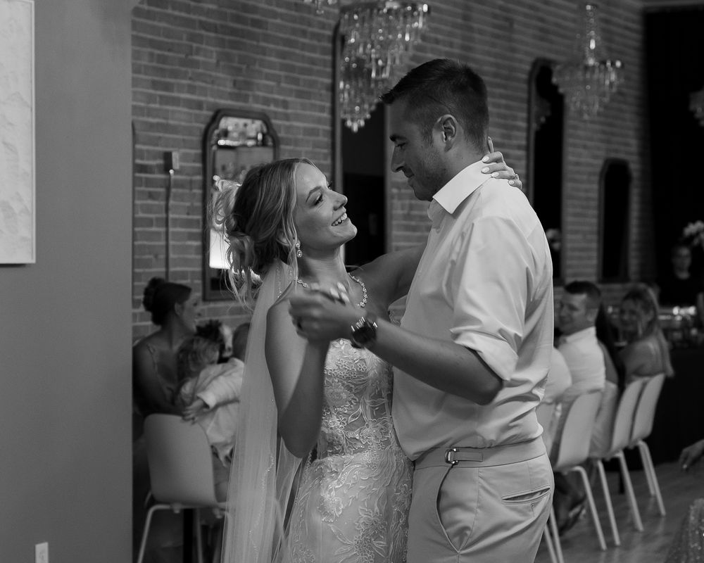 A couple shares an intimate dance moment at their wedding reception in black and white photography.