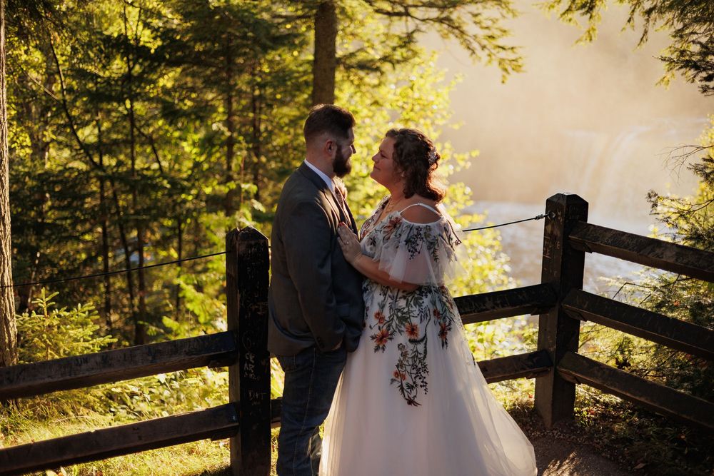 Wedding couple shares intimate moments along wooden fence with golden sunlight filtering through forest trees.