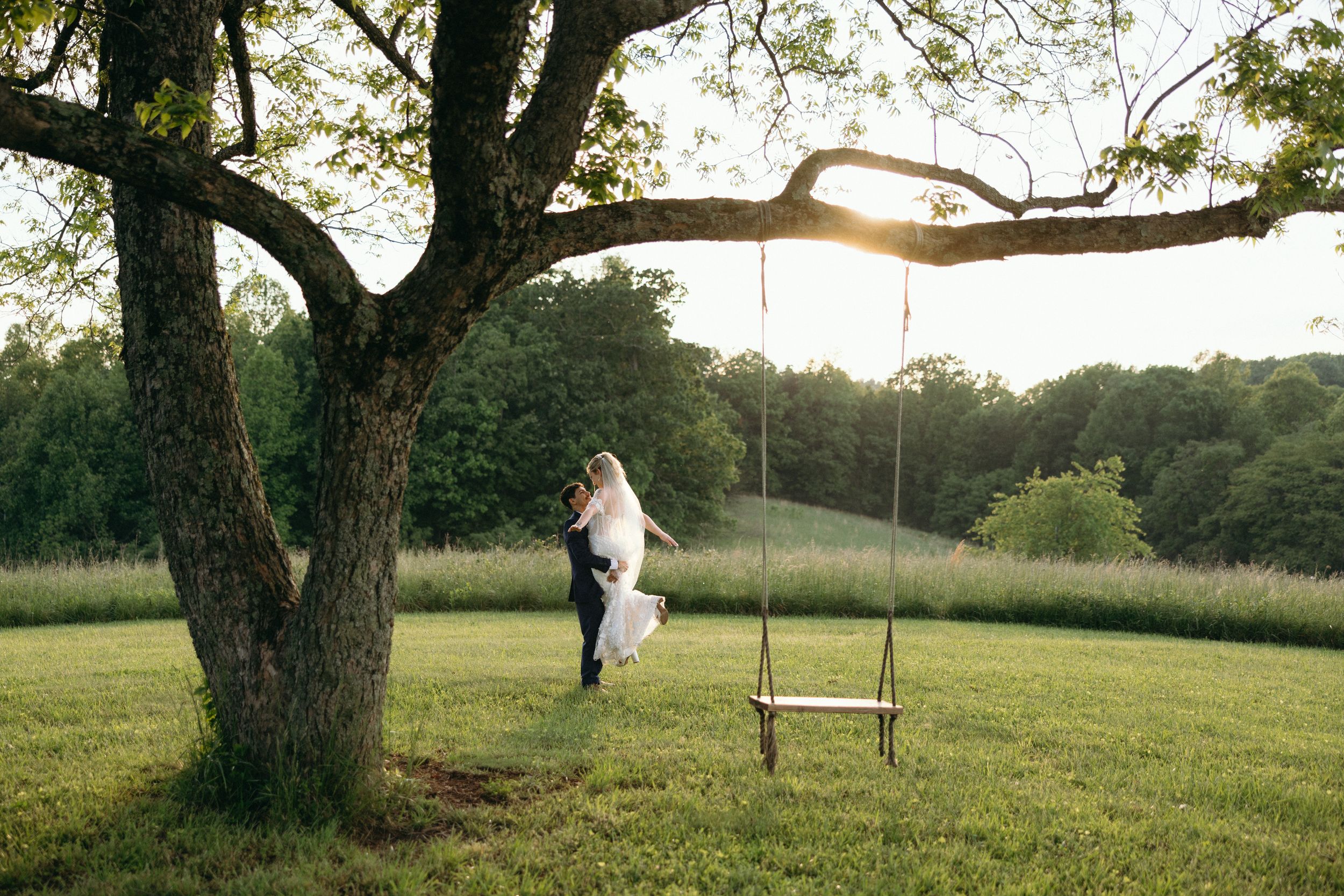 Tree swing photos at sunset create romantic silhouettes during outdoor wedding shoot. Estate and historic venue wedding photographer for NC