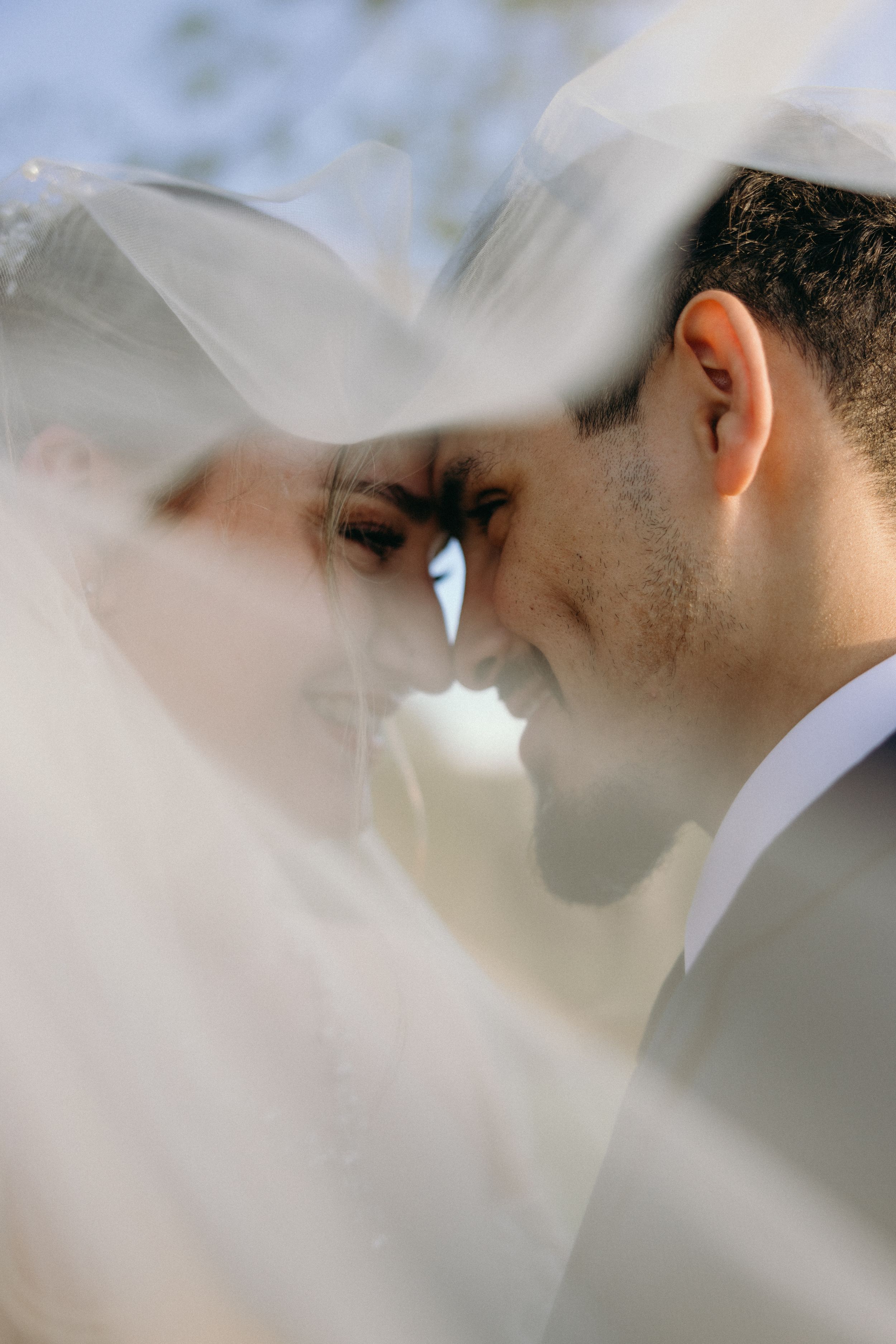 Artistic close-up shot through sheer white veil during intimate wedding moment. Estate and historic venue wedding photographer for NC