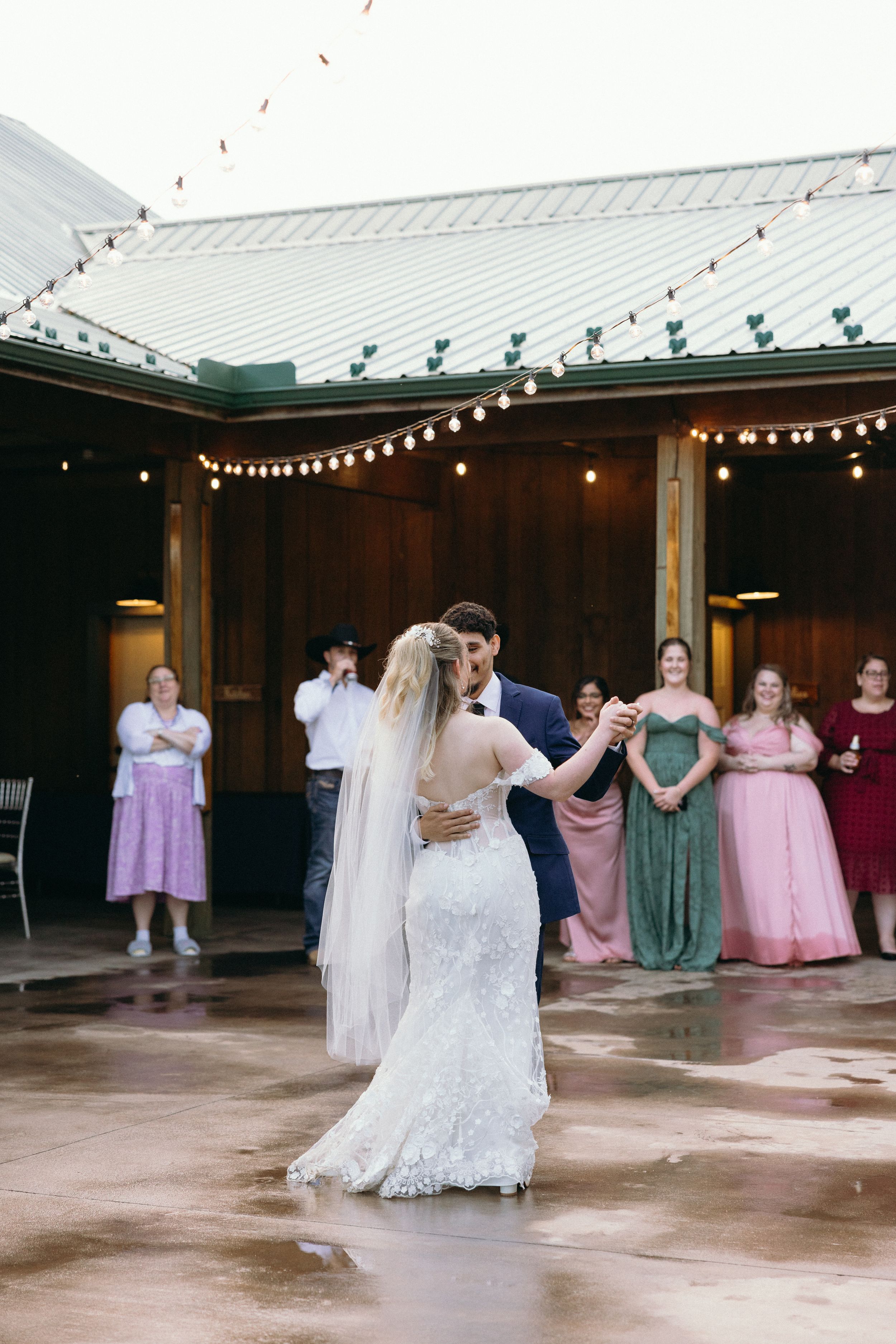 Wedding party dances in covered outdoor venue decorated with string lights. Estate and historic venue wedding photographer for NC