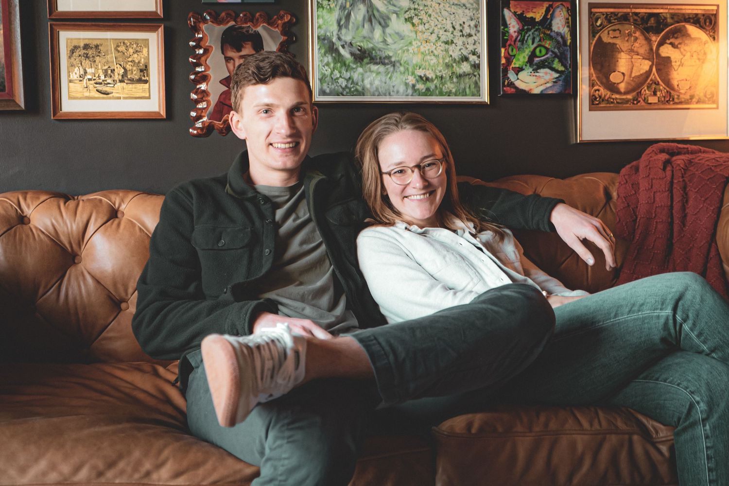 A series of artistic wall decorations and frames displayed in a dimly lit room. close up portrait of two adults.