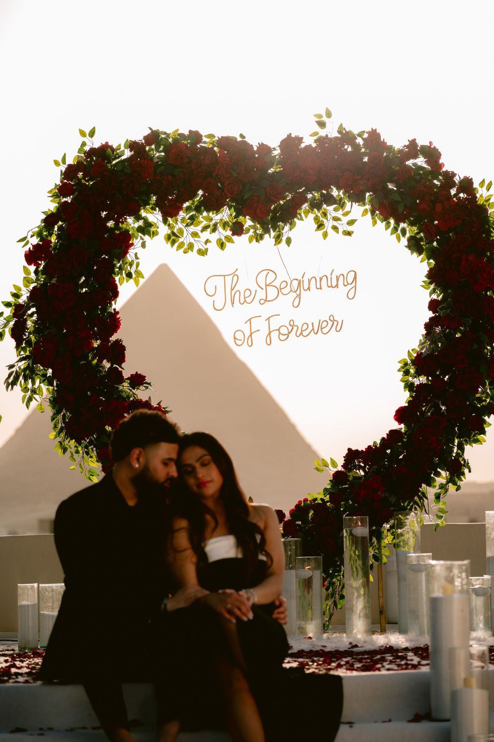 Romantic sunset silhouettes beneath decorative floral arches at an outdoor wedding venue.