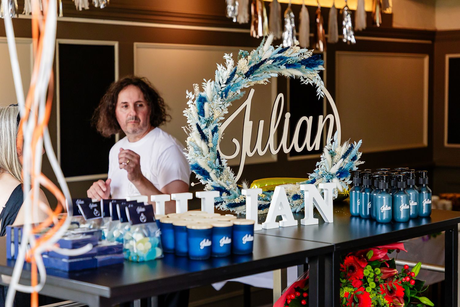Bar staff mix colorful cocktails at an elegant bar counter with blue lighting and glass displays.